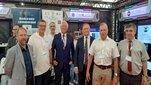 Grupa 7 stojących mężczyzn w hali wystawienniczej.