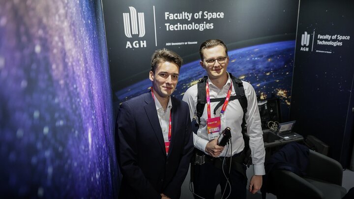 Two young men posing for a photograph inside a booth of the Faculty of Space Technologies.