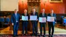 Zdjęcie grupowe: pięć osób prezentuje podpisane dokumenty w reprezentacyjnej sali