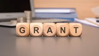 Image of five wooden cubes with letters making up the word "grant" lying on a desk
