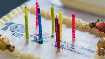 Photo of a cake with colorful candles, logo of the AGH University ACMiN Centre visible on the cake