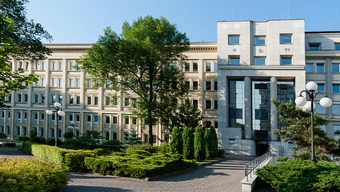 Zdjęcie jasnego budynku w otoczeniu zieleni. 