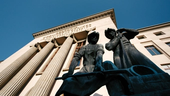 A monument of two steelworkers in front of the main building of AGH University