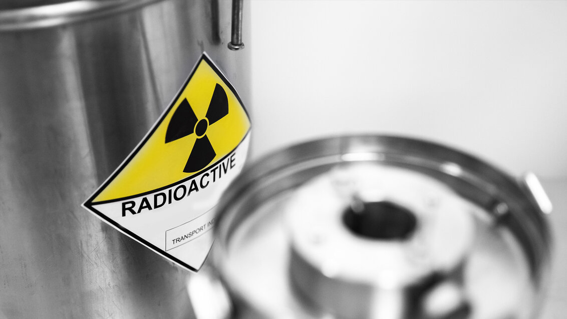 Zdjęcie przedstawia cylindryczne pojemniki w kolorze srebrnym na odpady radioaktywne. Na pojemnikach umieszczony jest czarny symbol radioaktywności na żółtym tle