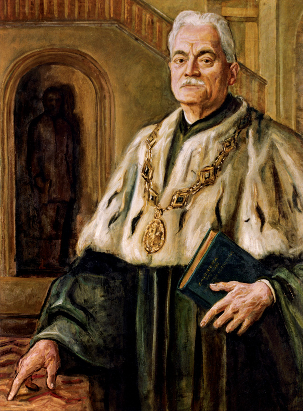 Portret Rektora Jana Anioła. Rektor ma na sobie zieloną togę, duży gronostajowy kołnierz oraz złoty ozdobny łańcuch. W ręce trzyma książkę. 