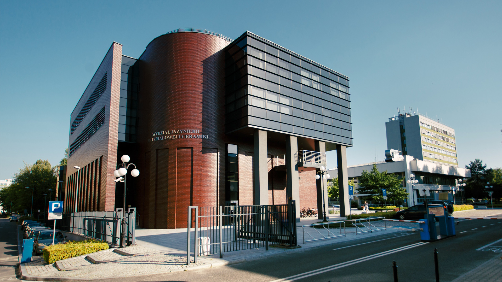 Photo of a modern building. The left elevation is made of dark red brick. The right side of the building has grey glass windows.