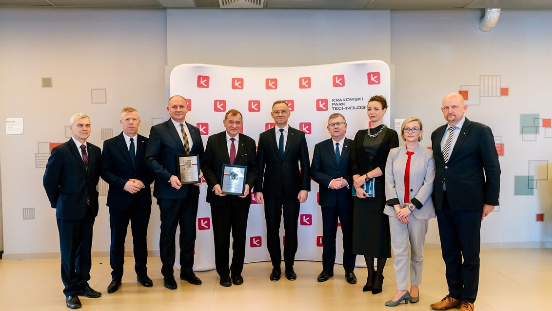 Image of a group of people posing for a photo in front of a photo wall; the people in the photo are the authorities of the Krakow Technology PArk, the AGH University, and the President of Poland