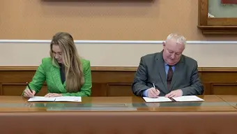 Image of a blonde woman in a green jacket and a man in a suit signing copies of an agreement; image of Marzena Maj and Professor Wiśniowski