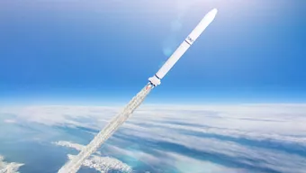 A white rocket that leaves a trail of exhaust fume that comes from the rocket nozzle. The rocket ascends into space, above the clouds, against a blue sky.