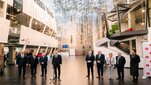 Image of two groups of people standing in a hall of a modern building, one of the people being the President of Poland